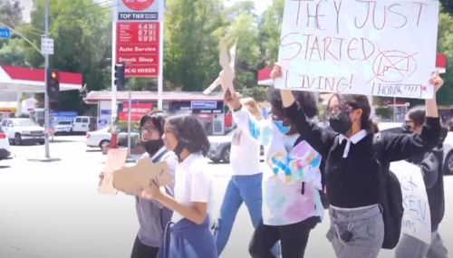 Students walk in protests with one holding an sign 